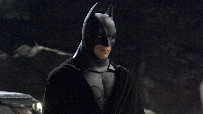 Christian Bale as Batman looking at someone off camera in Batman Begins.