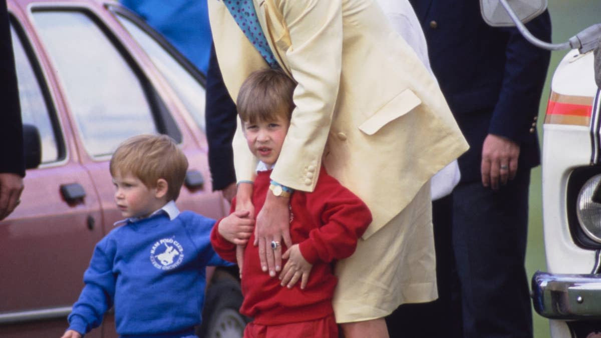 British Royals Diana, Princess of Wales (1961-1997), wearing a yellow suit with a Jasper Conran blouse, and her sons Prince Harry (in blue) and Prince William (in red) at the Guards Polo Club at Smiths Lawn, in Windsor Great Park, Windsor, Berkshire, England, 31st May 1987. Diana's Royal Protection Officer Ken Wharfe is visible in the background, to the right of the frame. (Photo by Tim Graham Photo Library via Getty Images)Tim Graham Photo Library via Getty Images