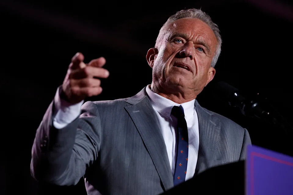 Man in a suit gestures while speaking at a podium during an event