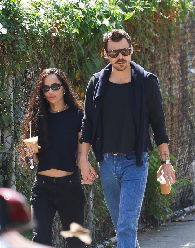 a couple walking handinhand while holding iced coffee drinks