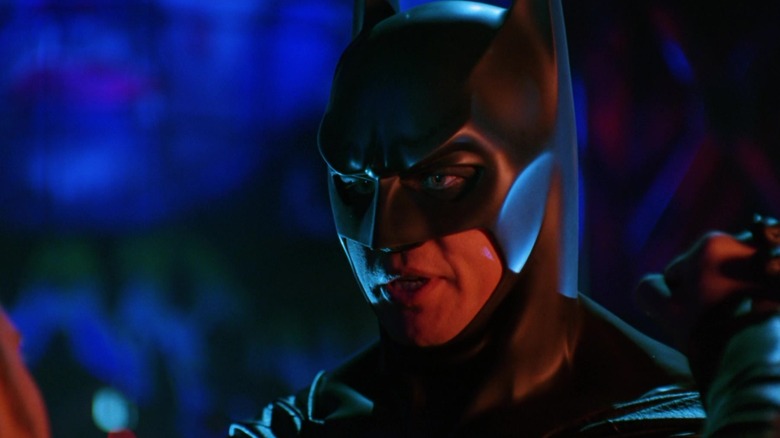 Val Kilmer's Batman stands in a neon lit alleyway in Batman Forever