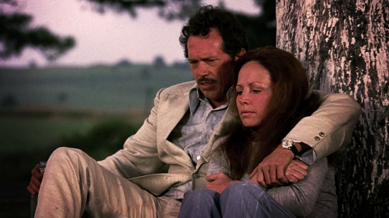 Bennie (Warren Oates) and Elita (Isela Vega) sitting against a tree in 