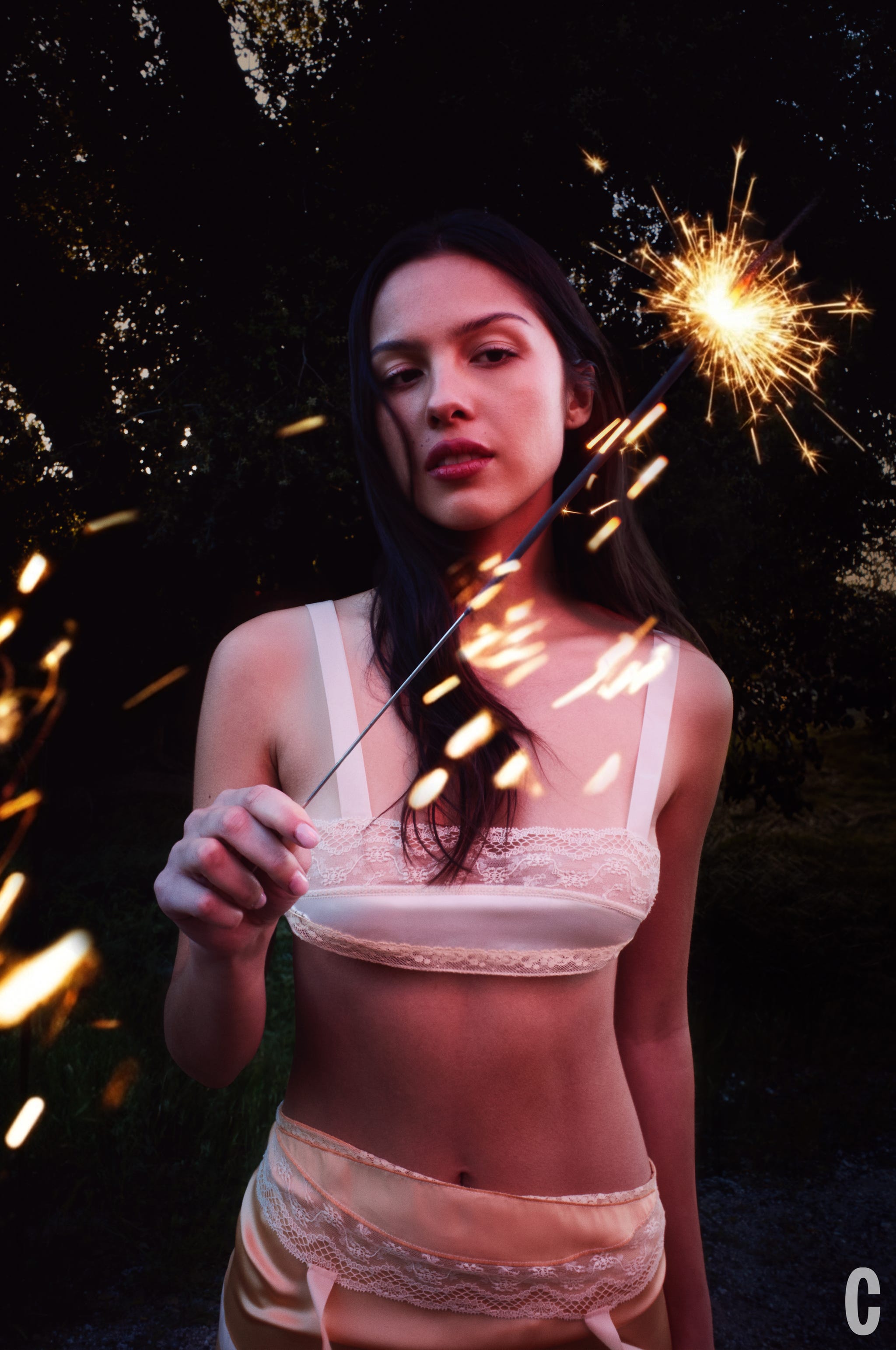 Person holding a sparkler in a dark outdoor setting.
