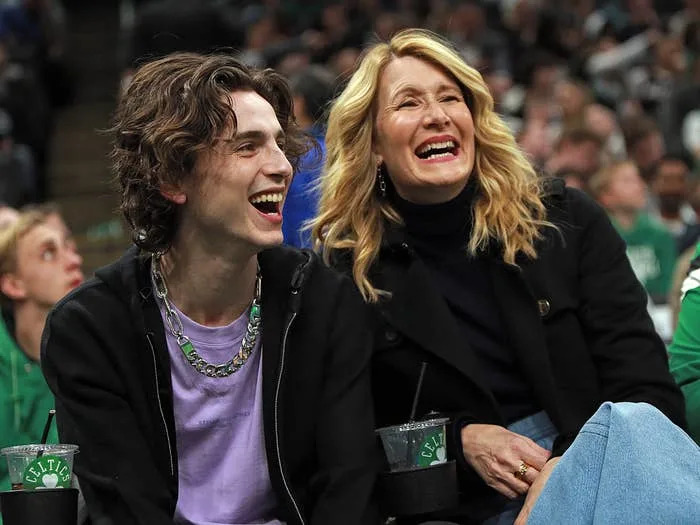 Two people sitting at a sports event, laughing and enjoying the game, surrounded by a crowd