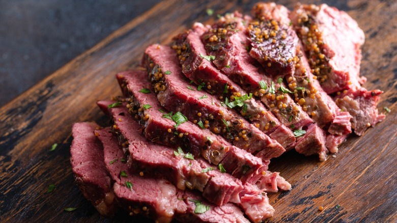 Sliced corned beef on a wooden cutting board.