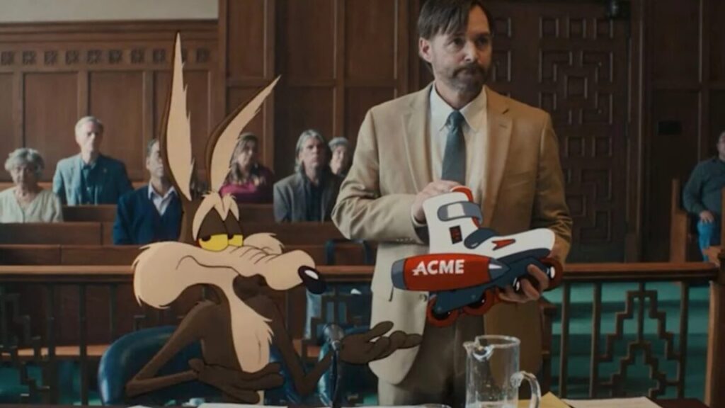 animated Wile E. Coyote seated in a courtroom while his lawyer holds up an Acme product