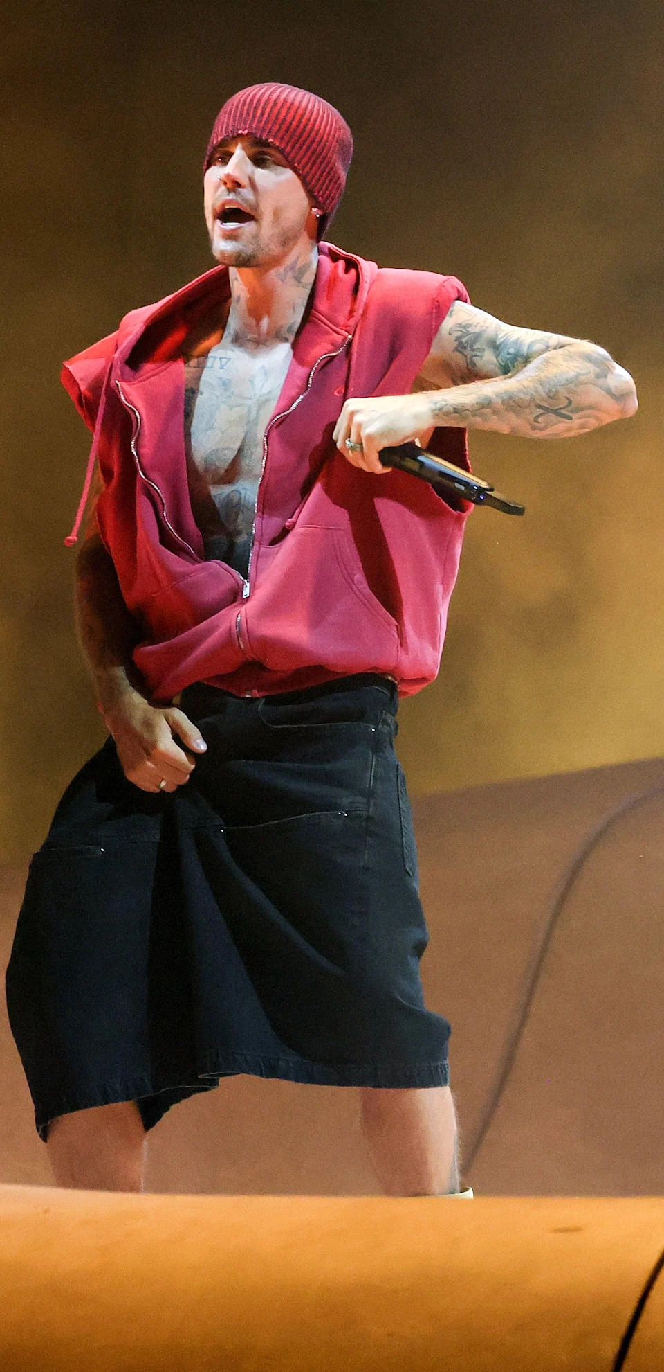 Justin Bieber in a sleeveless hoodie, shorts, and a cap onstage at Coachella