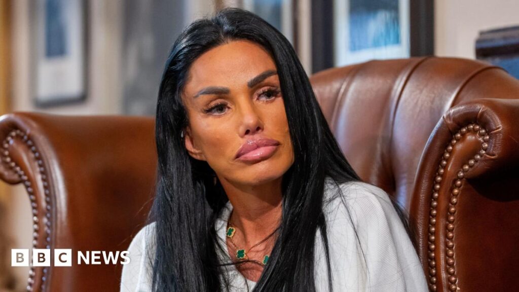 Katie Price banned from driving for seventh time Katie Price sitting on a brown leather chair. She has long, black hair and is wearing a gold and green necklace.
