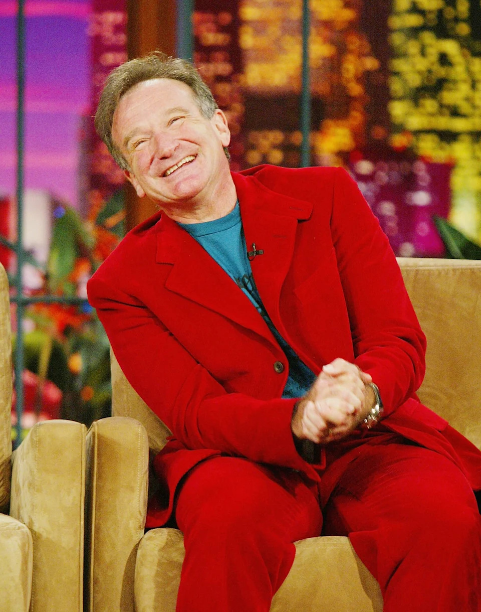 Person in a bold suit sitting and smiling warmly on a talk show set