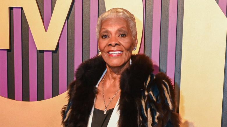 Singer Dionne Warwick standing in front of colorful  backdrop