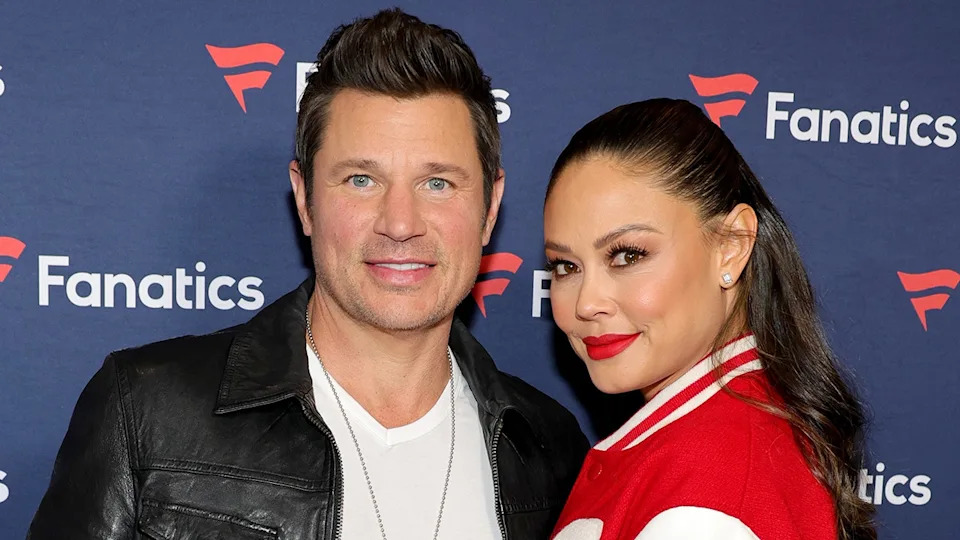 Nick Lachey smiling in a leather jacket with wife Vanessa Lachey in a red letterman jacket at a party