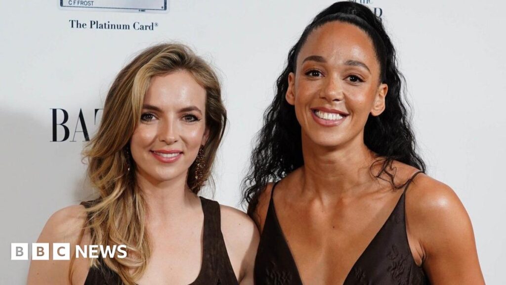 Jodie Comer and Katarina Johnson-Thompson pictured together at an awards ceremony where they are both wearing black dresses and smiling at the camera