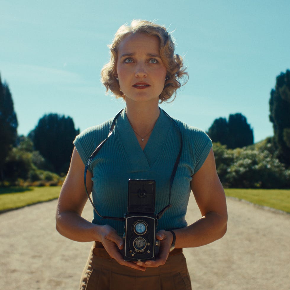 a person holds a vintage camera in a garden setting