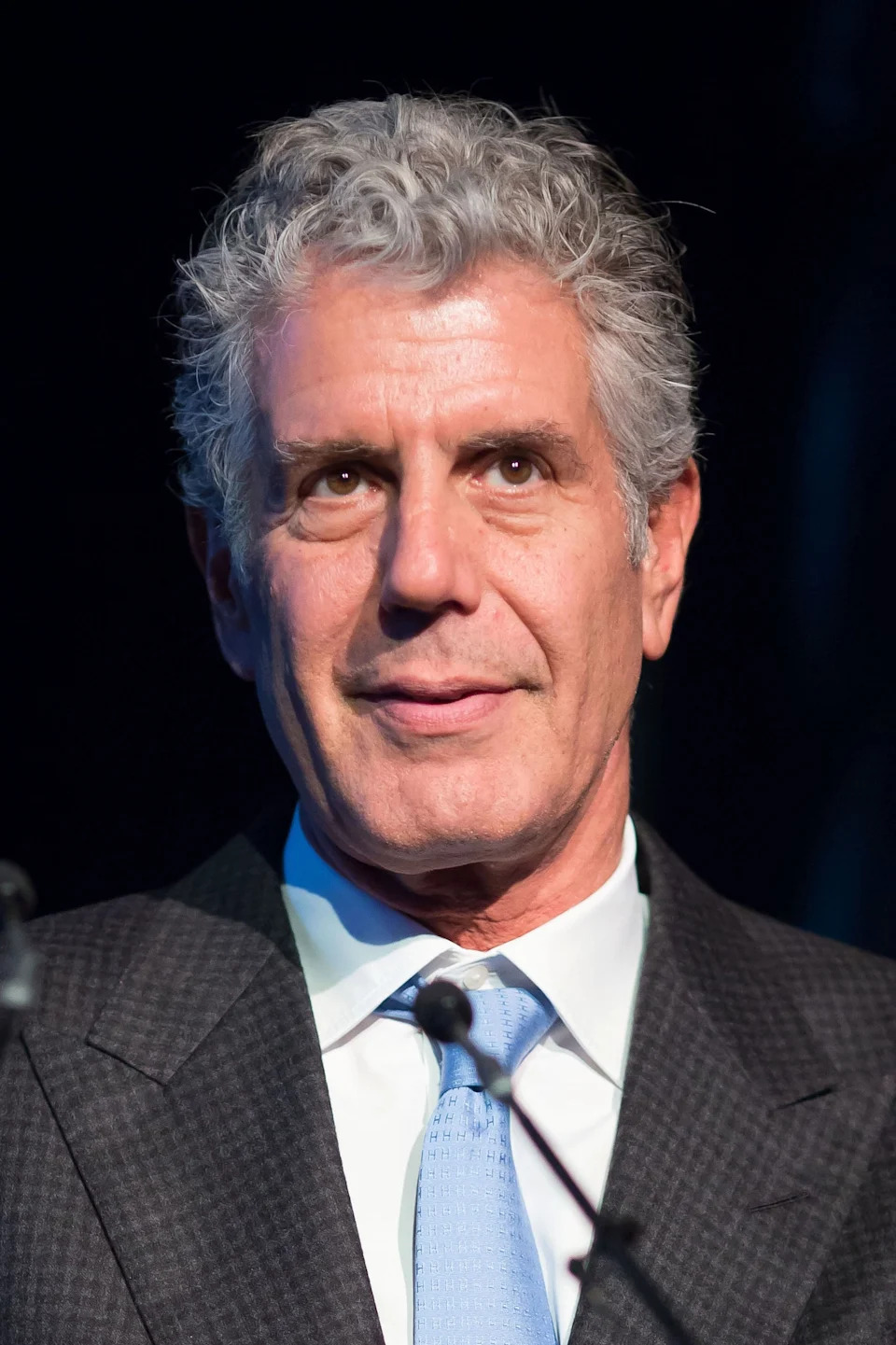 A man in a suit and tie is speaking at an event