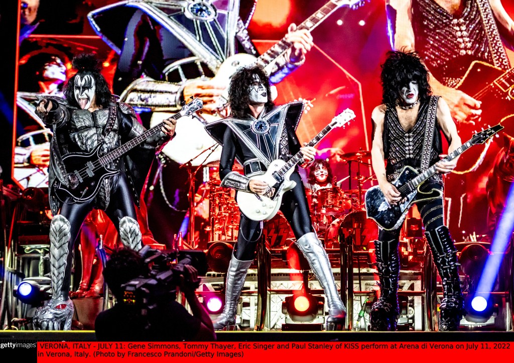 KISS performs on stage with Gene Simmons, Tommy Thayer, and Paul Stanley playing guitars, and Eric Singer on drums.