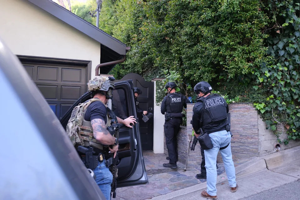 Armed officers approach a home in the Hollywood Hills.