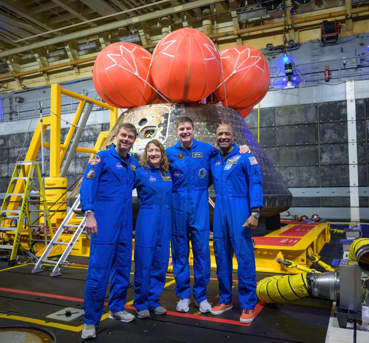The Artemis II astronauts pose for a group photo in front of their Orion Integrity spacecraft after splashdown.
