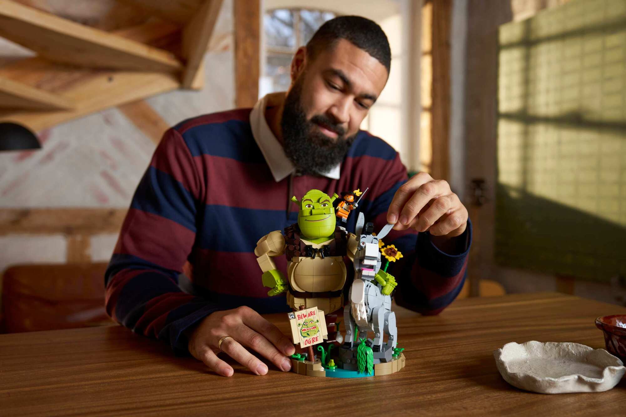 a person sits at a table building the Lego Shrek, Donkey & Puss in Boots