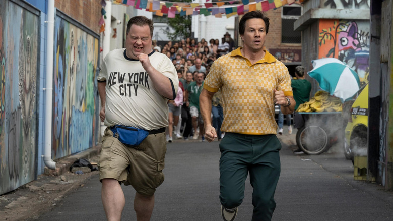 Paul Walter Hauser as Elijah and Mark Wahlberg as Brad running from a crowd in Balls Up