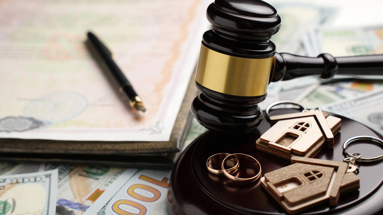Court documents, gavel, cash, and wedding rings on table
