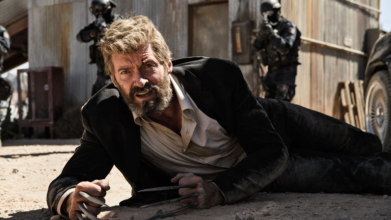 Hugh Jackman as Logan, laying in the ground surrounded by guards in Logan.