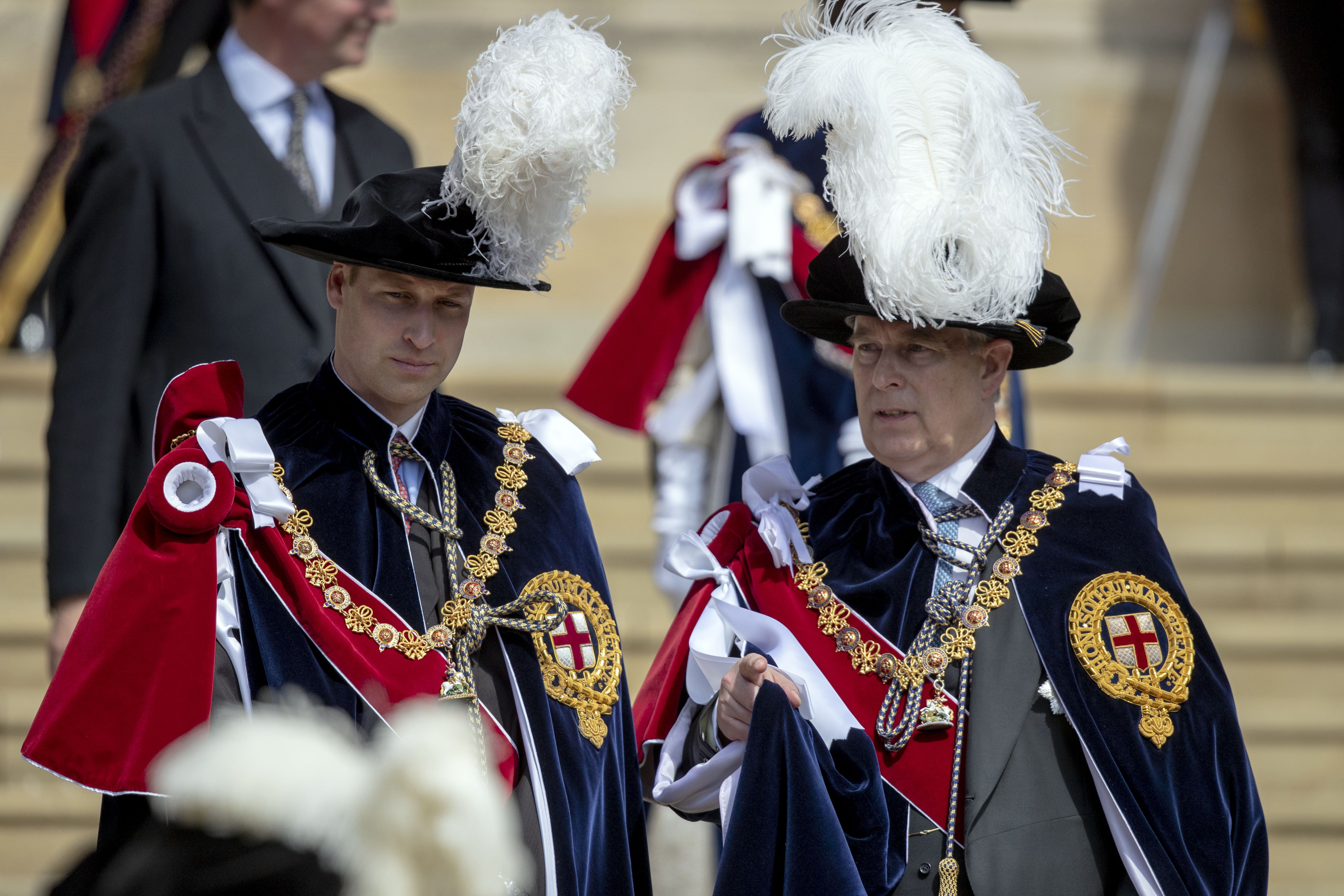 Prince William talking to Prince Andrew wearing plumed hats and capes