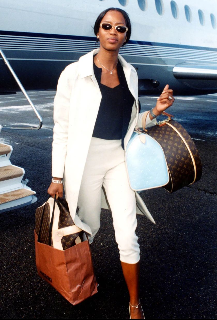 Naomi Campbell wearing a trench coat and capri trousers.
