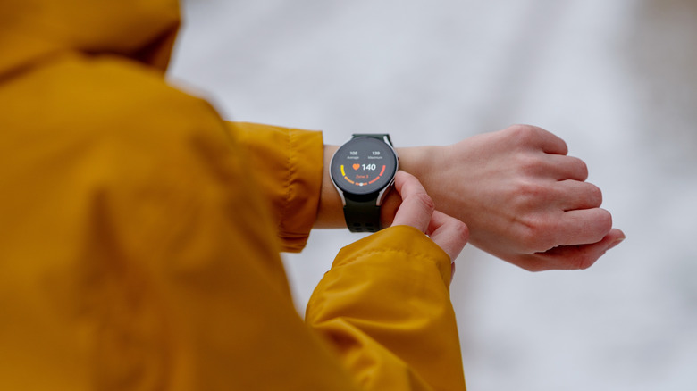 Person wearing smartwatch checking heart rate on wrist outdoors