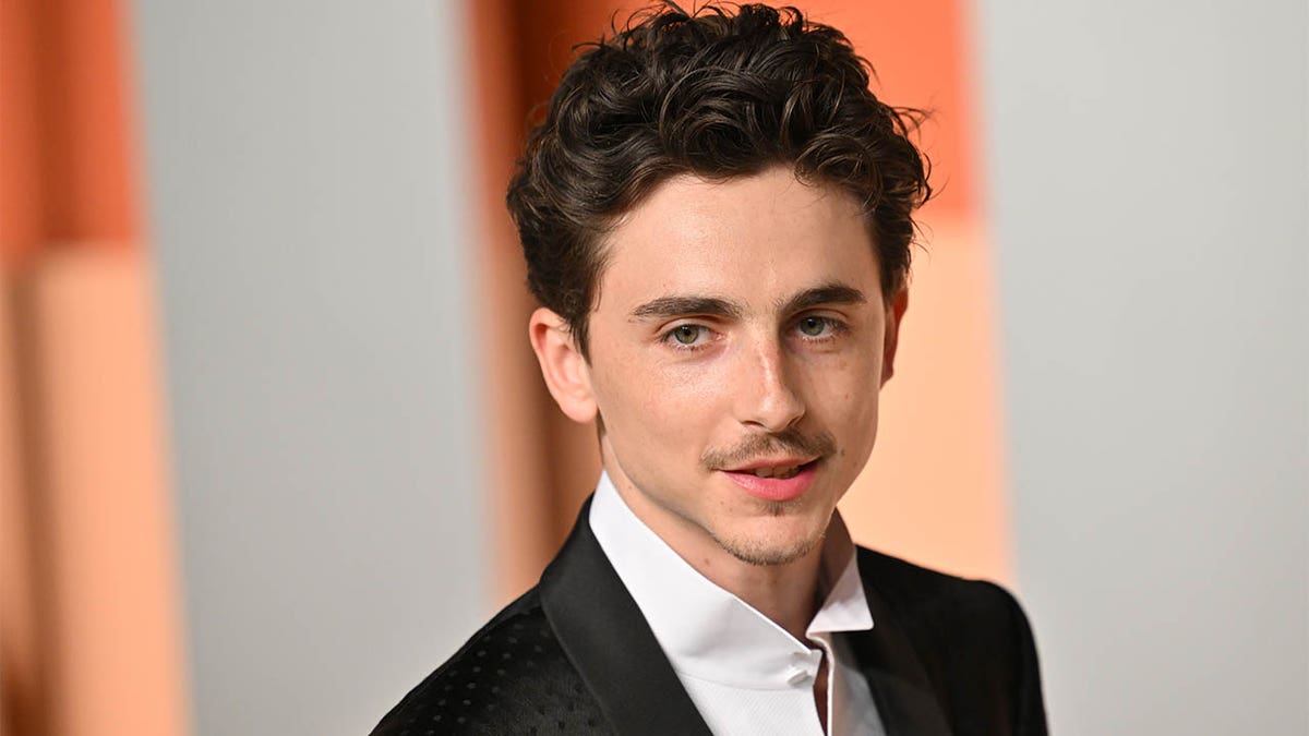 Timothée Chalamet standing at the Vanity Fair Oscar Party in Beverly Hills