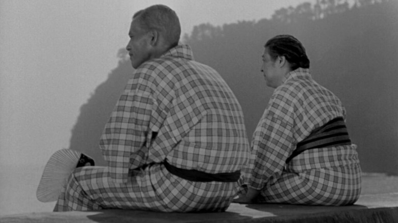 Chisū Ryū as Shūkichi Hirayama and Chieko Higashiyama as Tomi Hirayama in Tokyo Story, sitting on a ledge next to each other and looking out.