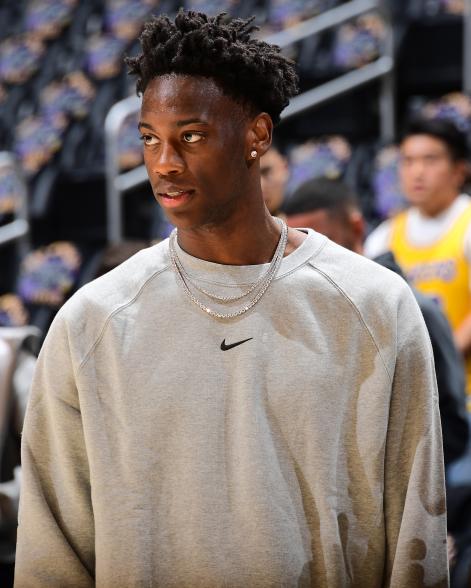 AJ Dybansta in a gray sweatshirt with two diamond necklaces and a diamond earring.