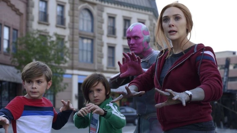 Julian Hilliard, Jett Klyne, Paul Bettany, and Elizabeth Olsen as Billy, Tommy, Vision, and Wanda Maximoff striking heroic stances as they prepare for battle in WandaVision