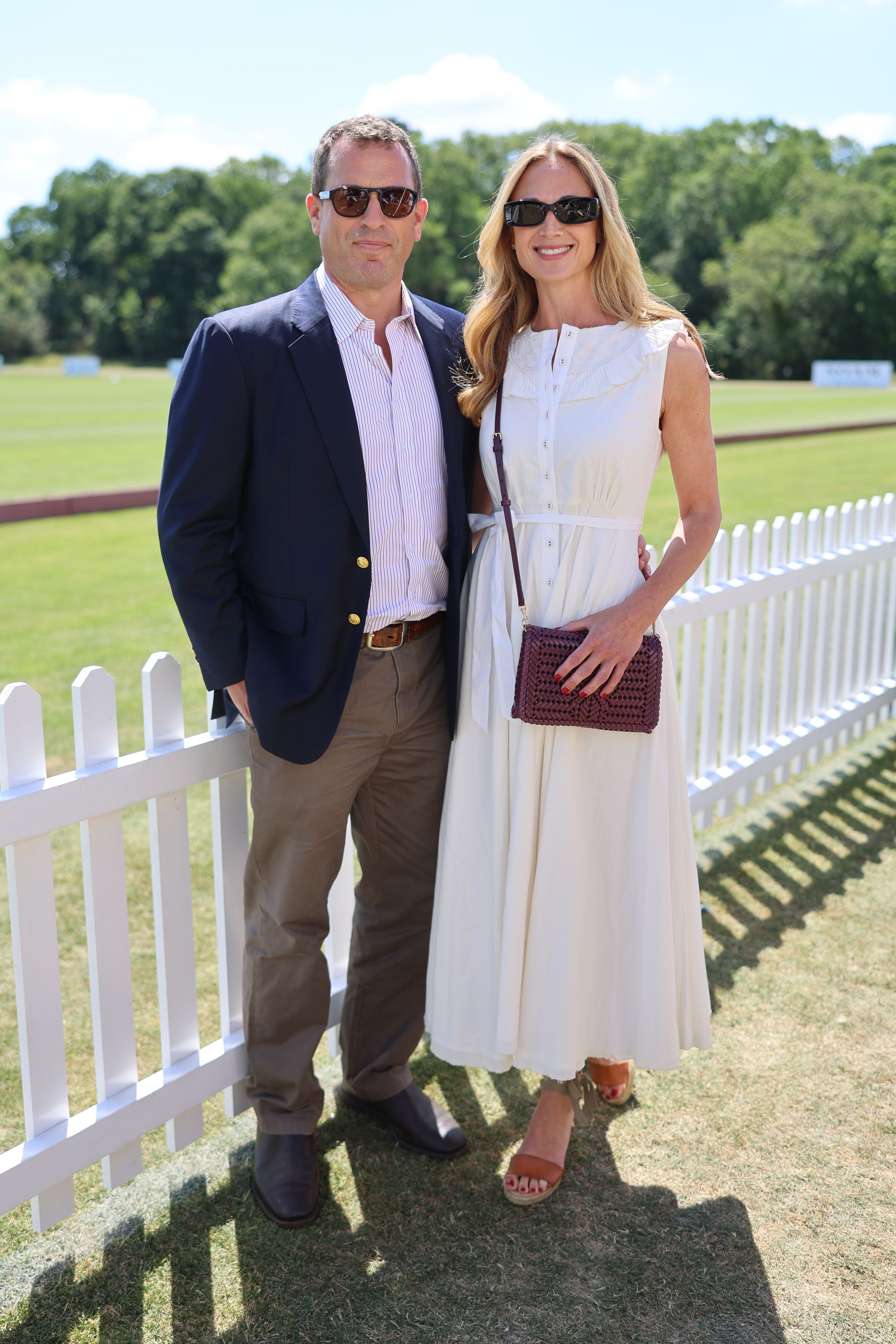 Harriet Sperling and Peter Phillips posing against a white fence at a polo field