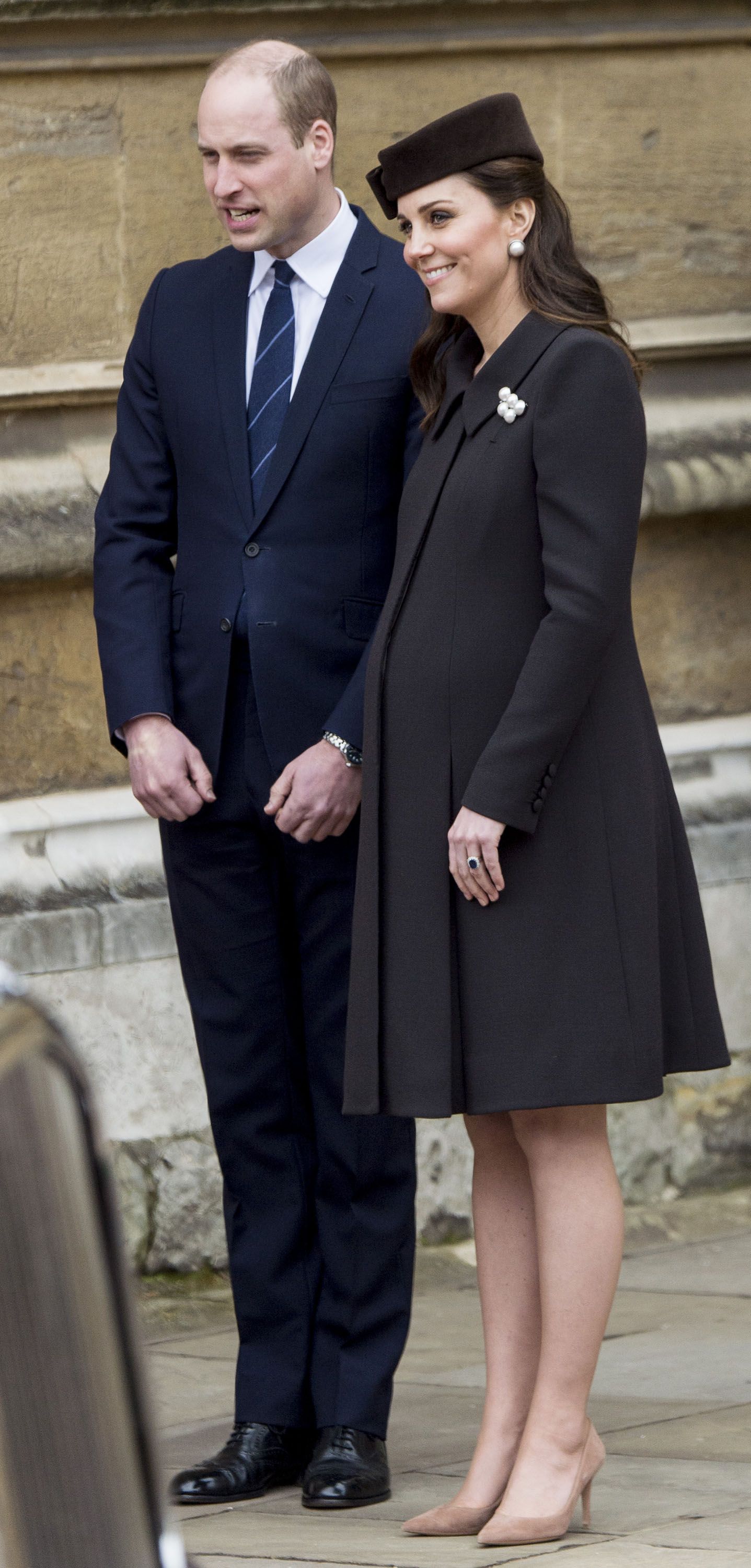 Princess Kate wearing a brown coat standing next to Prince William