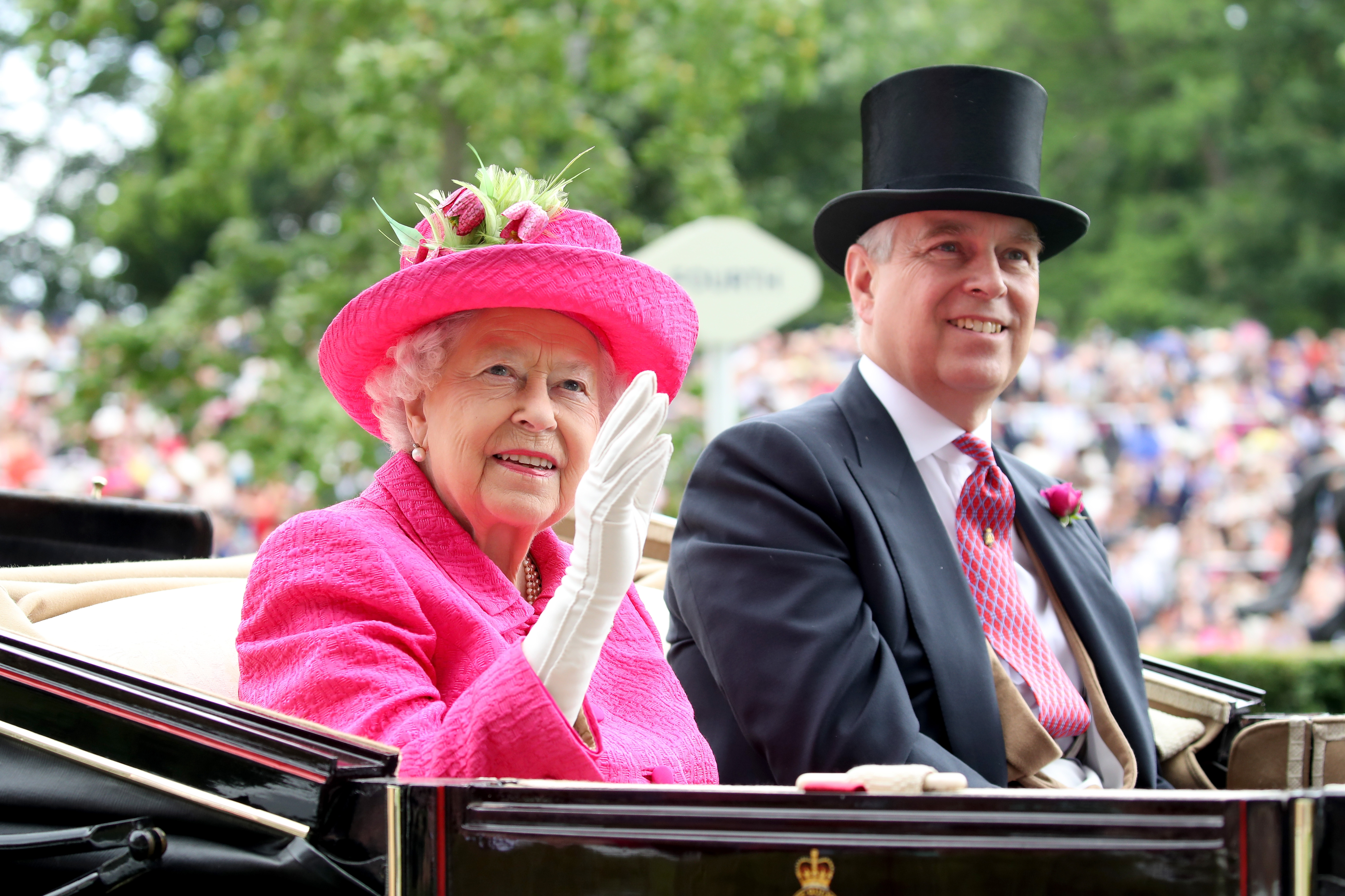 Queen Elizabeth waving in a carriage in a pink hat and coat next to ex-Prince Andrew