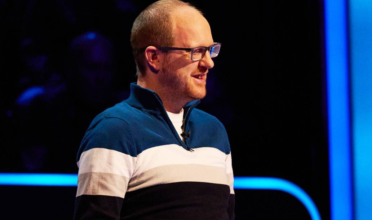 Man with glasses in striped zipped sweatshirt in blue and black studio