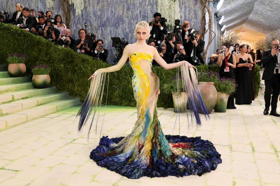 Emma Chamberlain wears a floor-length gown and feet of beaded fringe on her arms to the 2026 Met Gala.