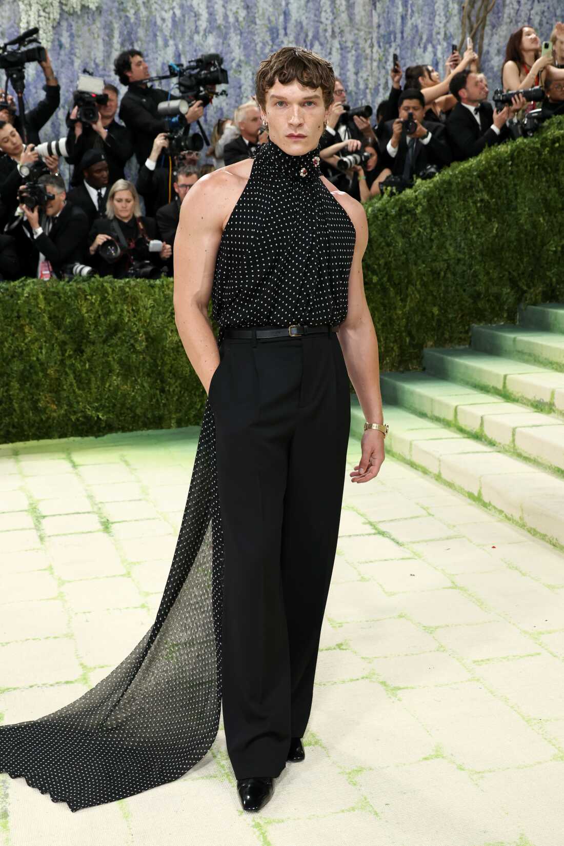 Actor Connor Storrie attends the 2026 Met Gala. He is wearing a black and white polka dot sleeveless top with black pants.