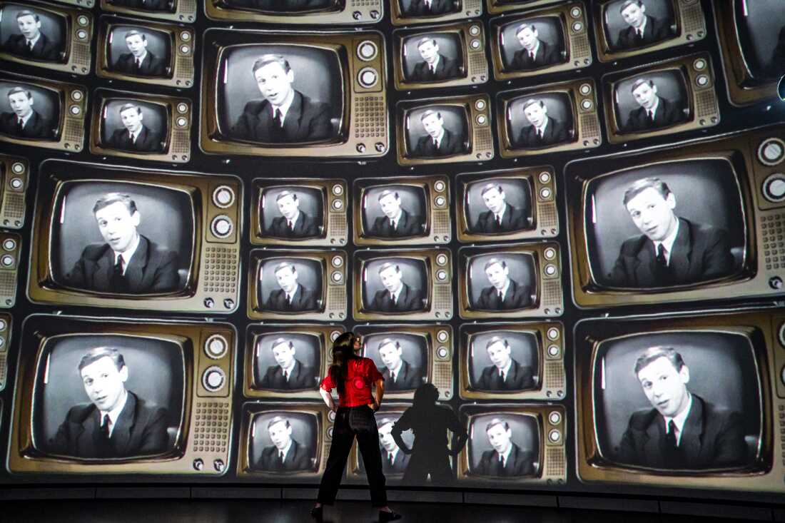 Head of creative enterprise, Maddie Hall, watches hundreds of television screens with David Attenborough's face, from when he was a young broadcaster, projected inside the dome within the Market Hall at Real Ideas in Devonport, Plymouth, England, where Hall and her team are making preparations for a public release of an immersive film to mark Attenborough's 100th birthday on Friday.