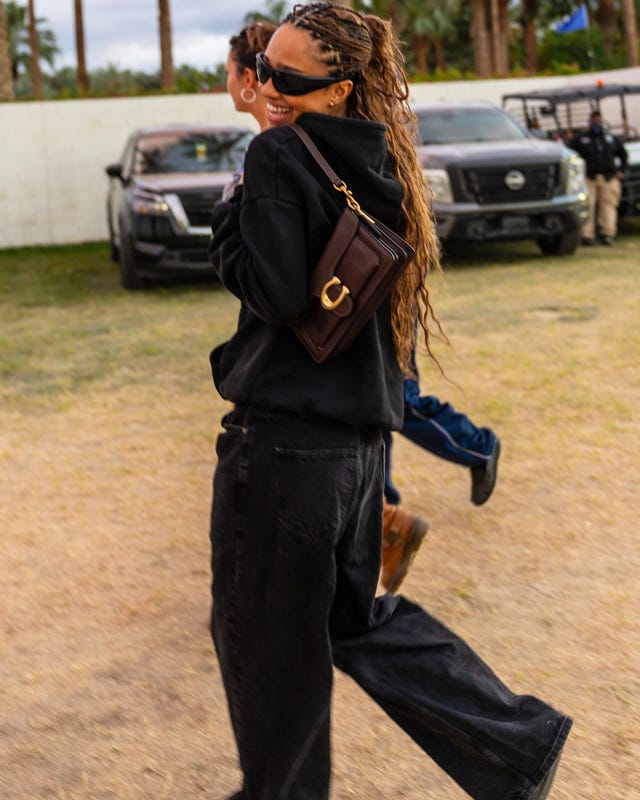 Person walking in a casual outfit with a small bag.