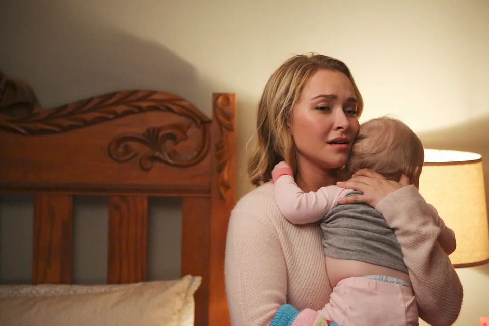 A woman looking upset holding a baby in her arms.