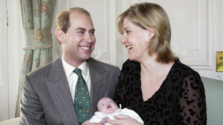 Prince Edward, Duke of Edinburgh and Sophie, Duchess of Edinburgh, smiling at each other while holding the newborn Lady Louise Windsor