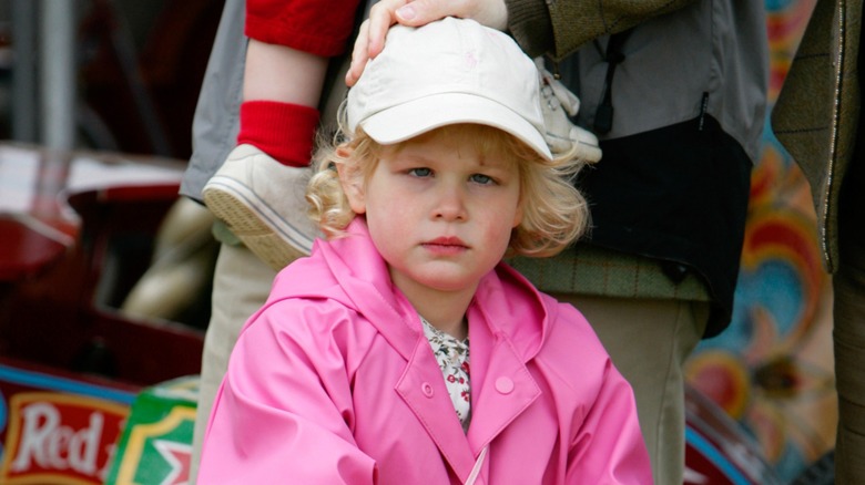 Young Lady Louise Windsor riding a bike and wearing a pink coat