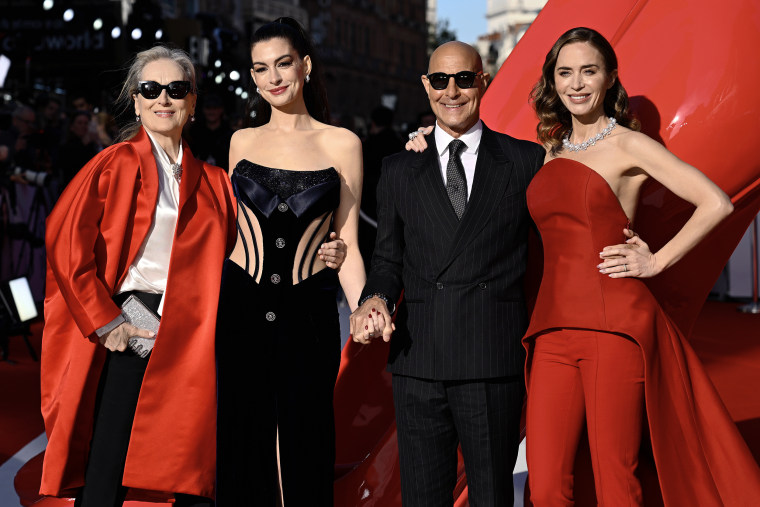 Meryl Streep, Anne Hathaway, Stanley Tucci and Emily Blunt pose for a photo together in red and black formal attire.
