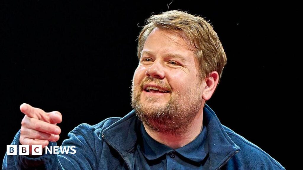 Gavin and Stacey’s James Corden singles out ‘awful’ episode James Corden has sandy blonde hair and a beard and moustache. He is wearing a blue jacket, blue polo shirt and is pointing off to the side of the camera.