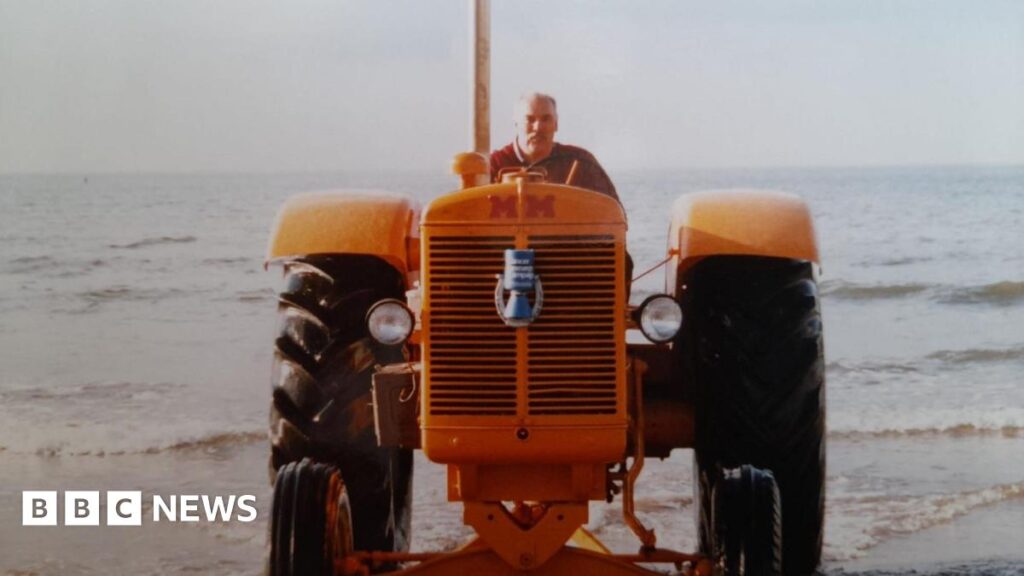 Hale farmer’s retirement plan to sell tractors ‘worth up to £500k’ Dave Harrison riding a yellow tractor parked on a beach.