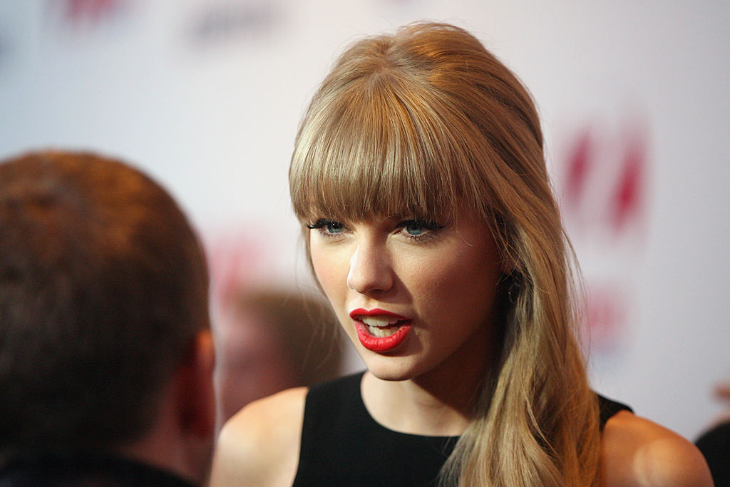 Taylor Swift speaking to a man with his back to the camera.