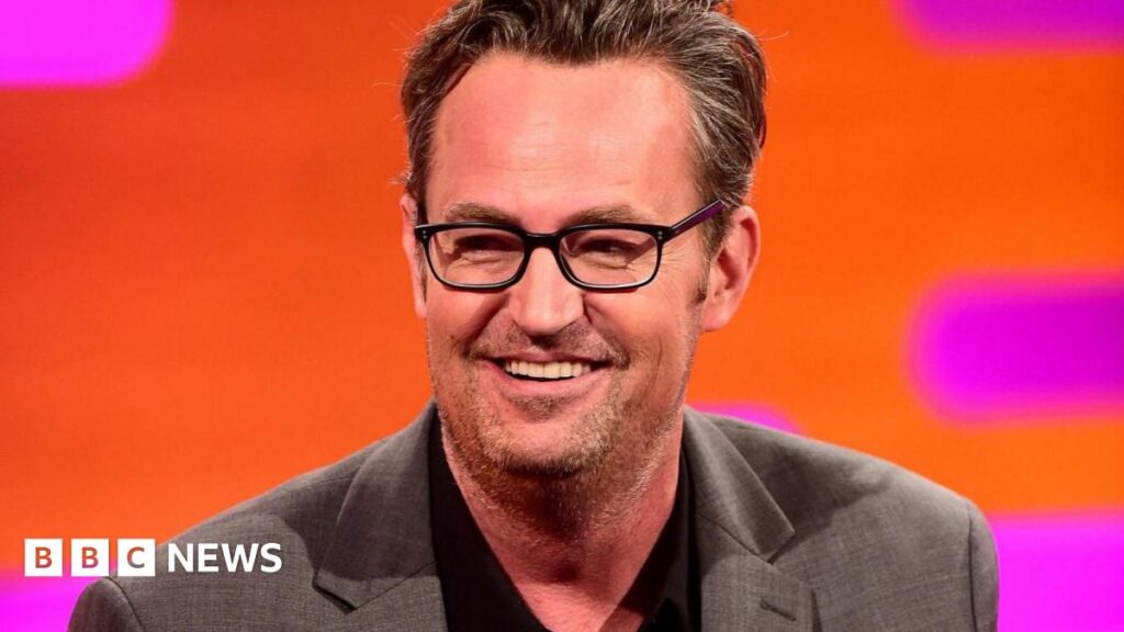 Actor Matthew Perry, wearing a grey suit jacket, speaking onstage at the 2017 Winter Television Critics Association Press Tour in Pasadena, California