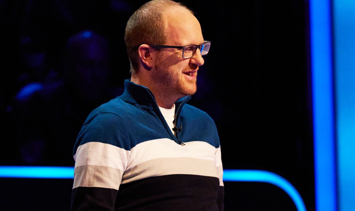 Man with glasses in striped zipped sweatshirt in blue and black studio