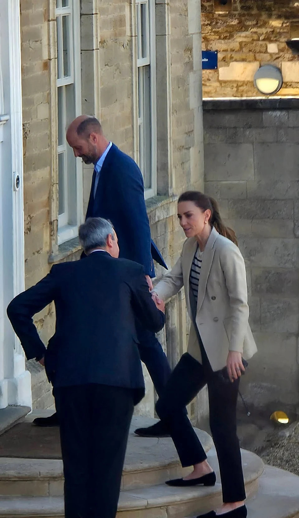 Princess Kate shaking hands with a man outside a house